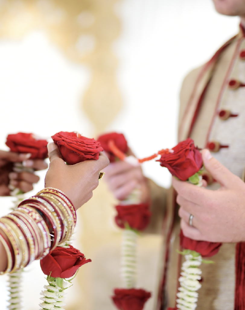 Couple exchanging rose garlands at a multicultural wedding